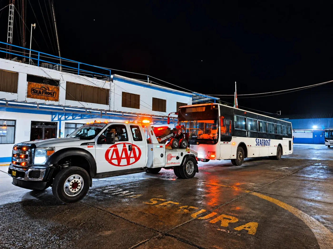 Grúa Famosa Triple A remolcando un bus de noche en Piura